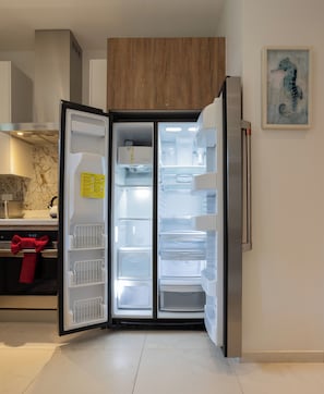 Une cuisine moderne avec un réfrigérateur encastré, un meuble en bois au-dessus et un tableau accroché au mur.