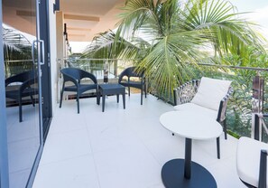 Un balcon avec une table blanche, deux chaises et un canapé.