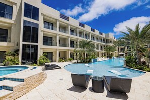 Un hôtel doté d’une piscine, d’un espace extérieur aménagé et d’un bâtiment à plusieurs étages avec des balcons.