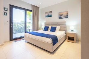 A bedroom with a bed, a nightstand, a window with curtains, and a view of the outdoors.