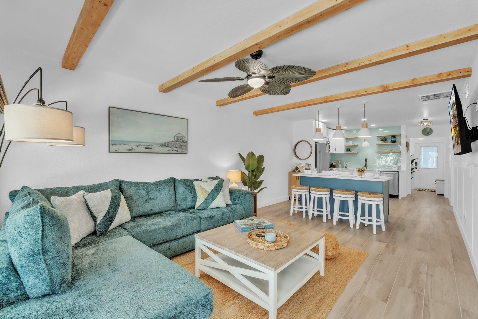 Una sala de estar moderna con un sofá color aguamarina, una mesa de centro de madera y un ventilador de techo.