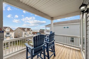 A covered balcony with two Adirondack chairs, a wooden deck, and a view of neighboring houses. - Beach Badger #147 - Rate Reduction! Ocean View Private Hot Tub, Dog Friendly! (North Topsail Beach)