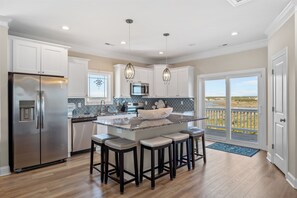 A modern kitchen with a central island, stainless steel appliances, and a view to the outdoors. - Beach Badger #147 - Rate Reduction! Ocean View Private Hot Tub, Dog Friendly! (North Topsail Beach)