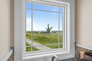 A window with a view of a road and greenery. - Beach Badger #147 - Rate Reduction! Ocean View Private Hot Tub, Dog Friendly! (North Topsail Beach)