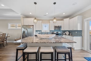 A kitchen with a central island, bar stools, and pendant lighting. - Beach Badger #147 - Rate Reduction! Ocean View Private Hot Tub, Dog Friendly! (North Topsail Beach)