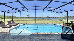 Una piscina cubierta al aire libre con vistas a un lago y edificios lejanos.