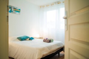 Une chambre à coucher avec un lit, des oreillers, une serviette enroulée et une table de chevet.
