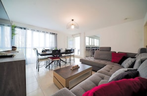 A modern living room with a sofa, coffee table, and dining area. - Bright apartment • 3 bedrooms • Vosges & cycling (Thann)
