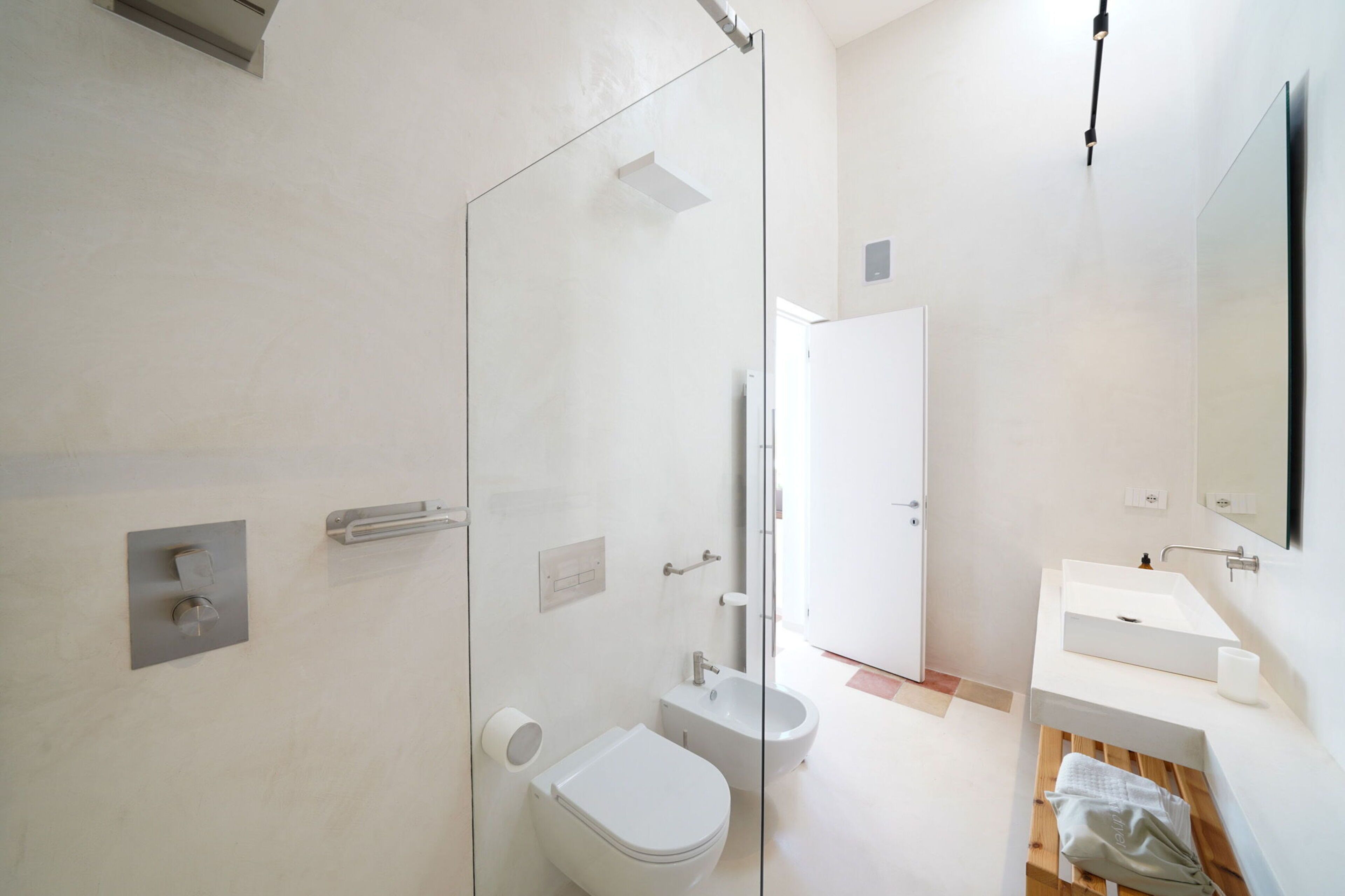 Un baño moderno con cabina de ducha de vidrio, inodoro, bidé y lavamanos con espejo.