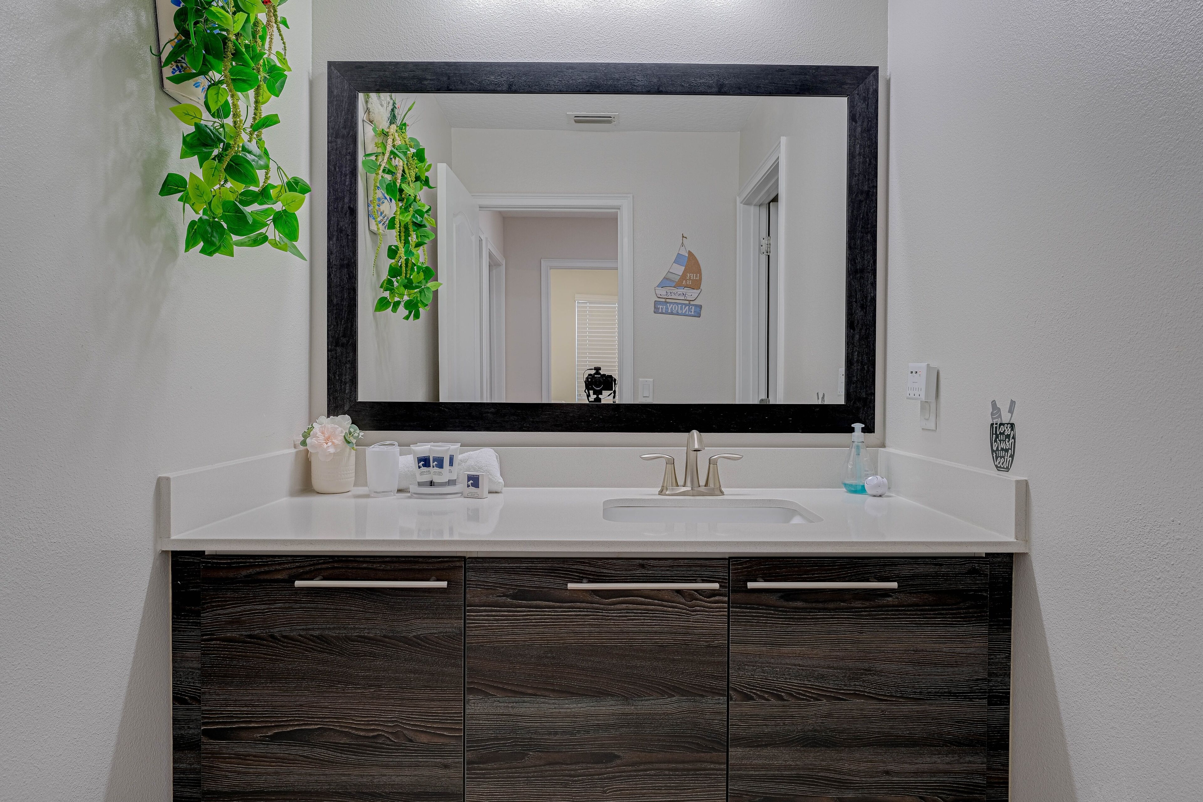 Une salle de bain avec un lavabo blanc, des meubles en bois foncé et un grand miroir.