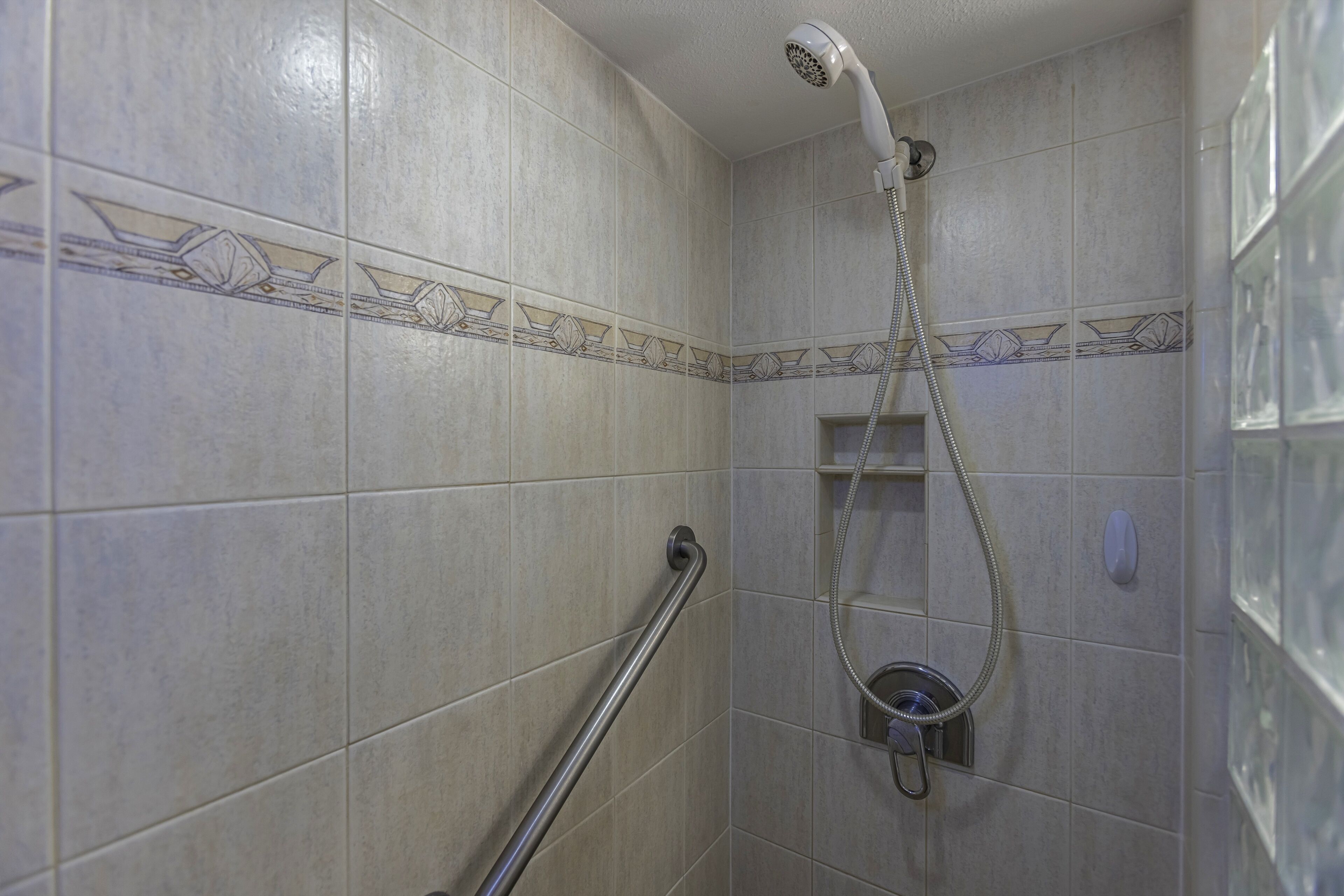 A shower with a handheld showerhead and a handheld shower attachment.