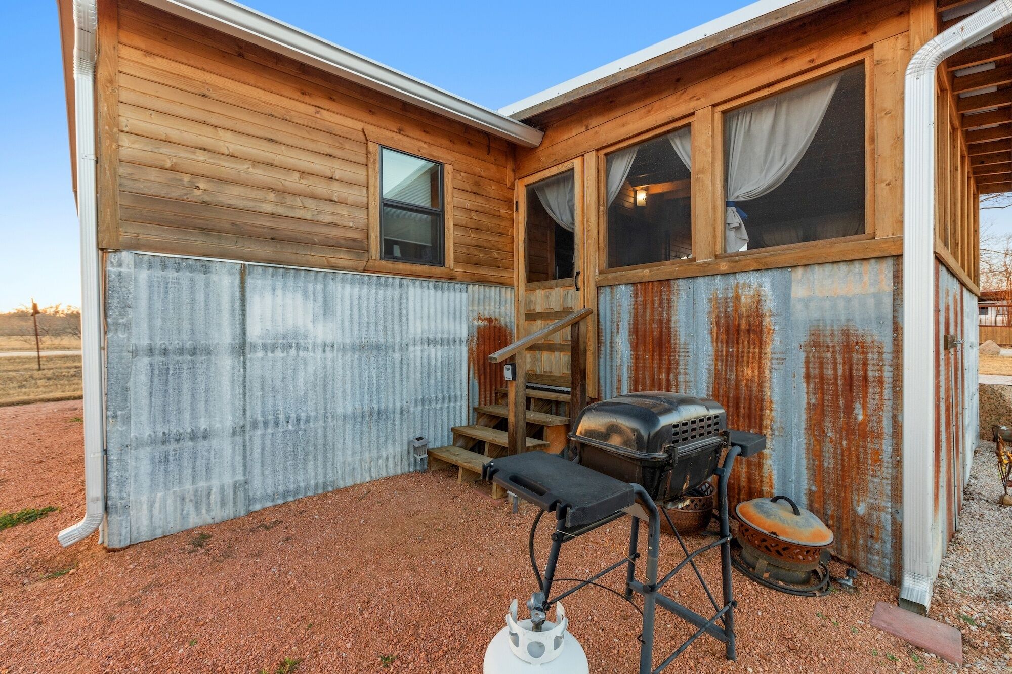 A rustic cabin with wooden walls, a metal exterior, and a chimney.