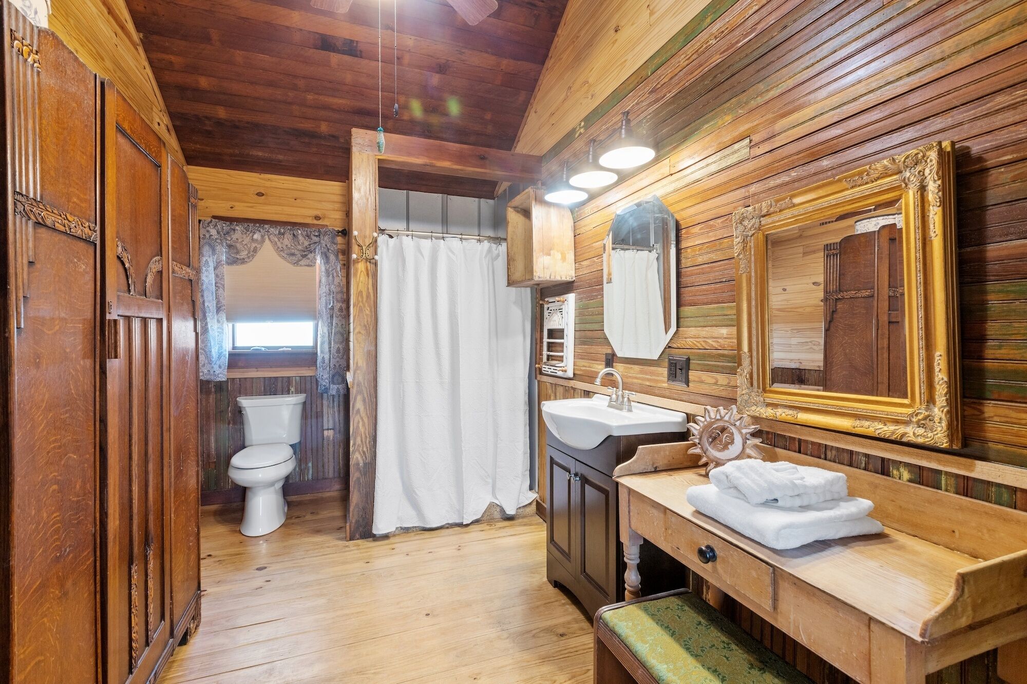 Een houten badkamer met toilet, wastafel en spiegel.