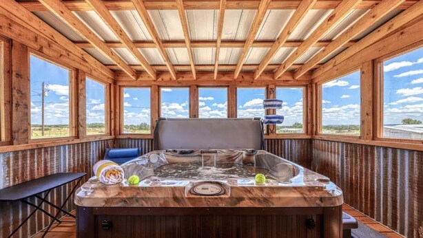 Un jacuzzi en una cabaña de madera con ventanas amplias y vistas al cielo.