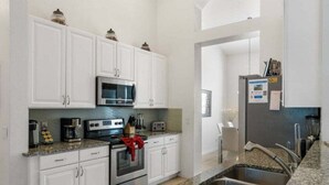 A modern kitchen with white cabinets, a stainless steel oven, a microwave, and granite countertops. - Last Minute Disney! Private Pool, Game Room & Themed Bedrooms. Book Now! #93821 (Orlando)