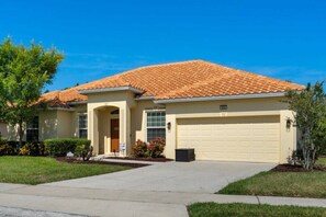 A residential house with a tiled roof, a garage, and a well-maintained lawn. - Last Minute Disney! Private Pool, Game Room & Themed Bedrooms. Book Now! #93821 (Orlando)