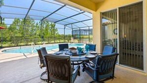 A covered patio with a pool, outdoor seating, and a view of the surrounding landscape. - Last Minute Disney! Private Pool, Game Room & Themed Bedrooms. Book Now! #93821 (Orlando)