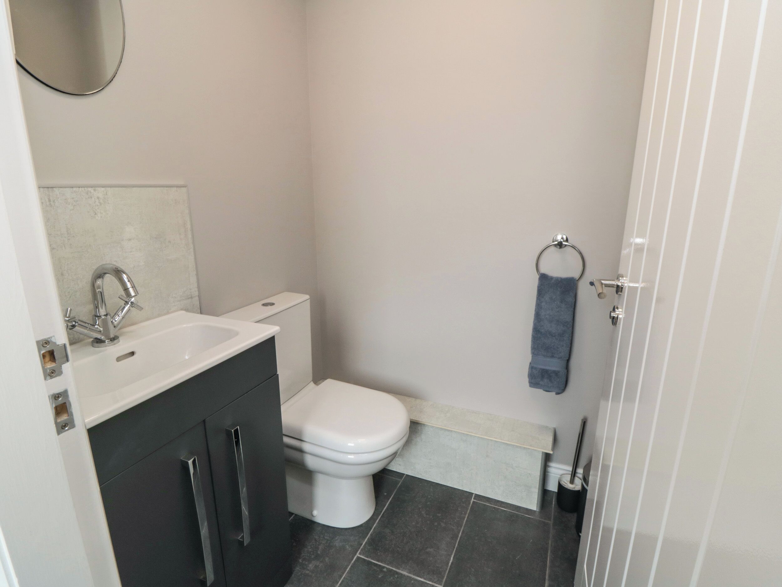 A compact bathroom with a white sink, dark cabinets, a white toilet, and a towel rack.