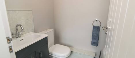 A compact bathroom with a white sink, dark cabinets, a white toilet, and a towel rack.