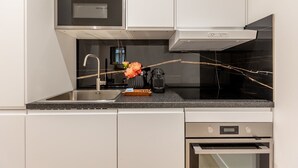 Une cuisine moderne dotée d’appareils électroménagers en acier inoxydable, d’un plan de travail en marbre et d’un four encastré.