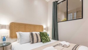 Une chambre d’hôtel avec un lit, une table de chevet avec une bouteille d’eau, un miroir et une fenêtre avec des rideaux.