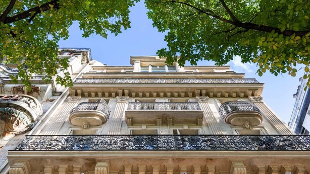 A classical building with ornate balconies and detailed stonework.