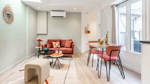 A modern living room with a sofa, coffee table, and dining area.