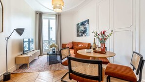 Een moderne woonkamer met een bank, stoelen, een salontafel, een vloerlamp en een schilderij aan de muur.