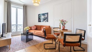 Een moderne woonkamer met een bank, stoelen, een salontafel en een eettafel.
