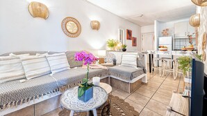 A modern living room with a sofa, a coffee table, and a dining area with stools.