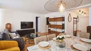 A modern living room with a dining area, a TV, and a large pendant light. - Sublime 3 bedrooms flat center of Paris Montmartre (Paris)
