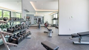 A modern gym with various exercise equipment, including dumbbells, benches, and cardio machines.