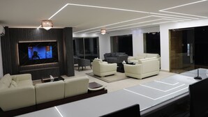 A modern living room with a flat-screen TV, white sofas, and a minimalist design. - Hotel San Diego (Kfar Yassine)