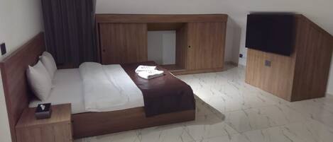 A hotel room with a bed, a nightstand, a wooden wardrobe, and a built-in bench.