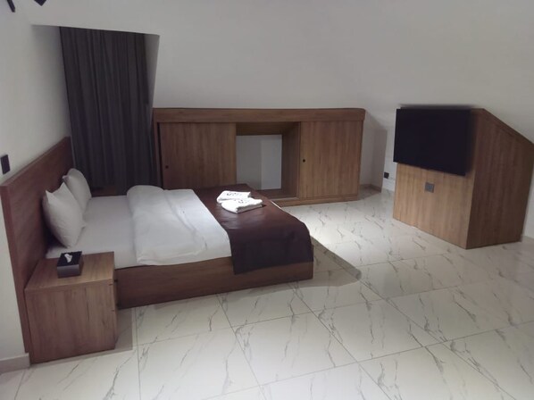 Una habitación de hotel con una cama, una mesita de noche, un armario de madera y un banco empotrado.