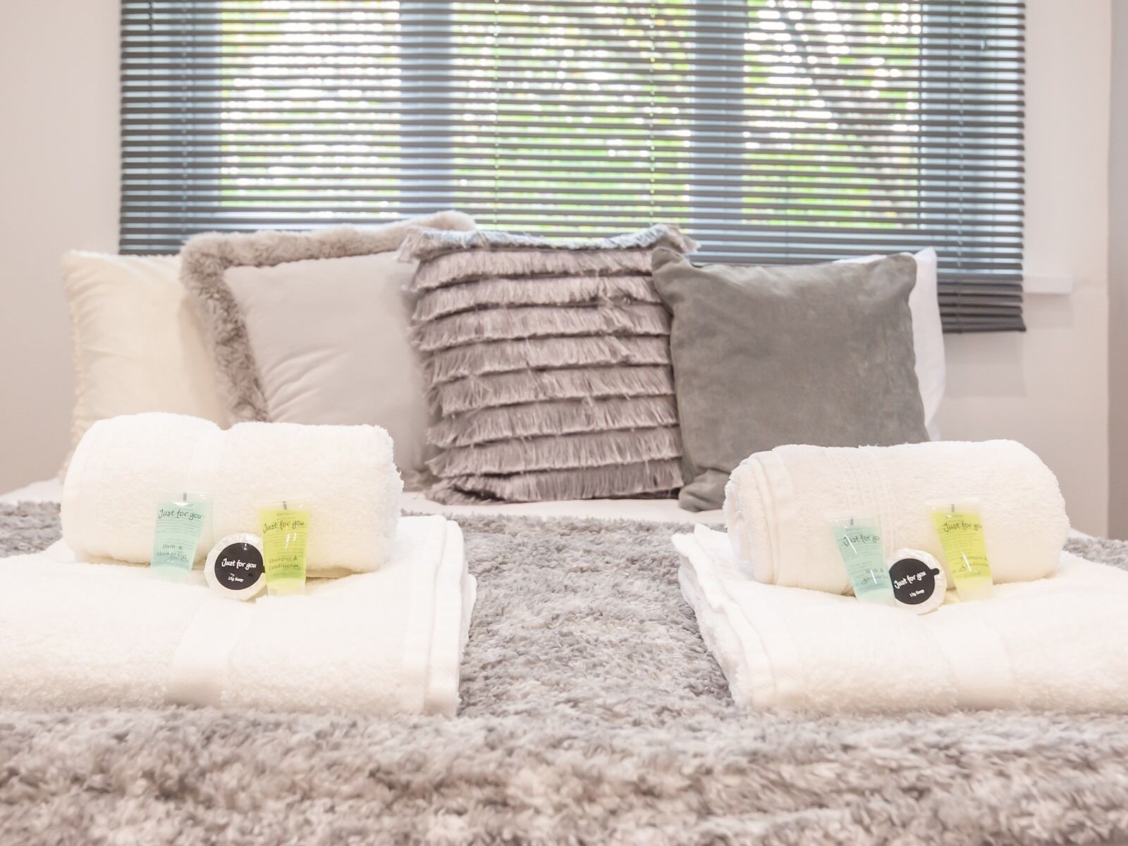 A bedroom with a large window, a fluffy rug, and two towels with 'Just for you' labels.