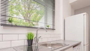 A kitchen with a sink, a potted plant, a stainless steel faucet, and a built-in washing machine.