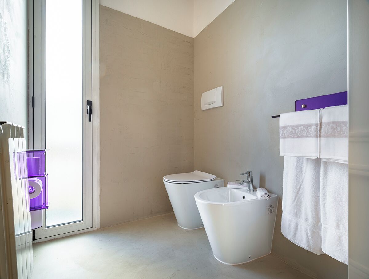 A bathroom with two toilets, a sink, and a towel rack.