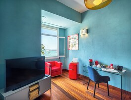 Una sala de estar moderna con televisor, sofá rojo y una mesa de vidrio con varios objetos.