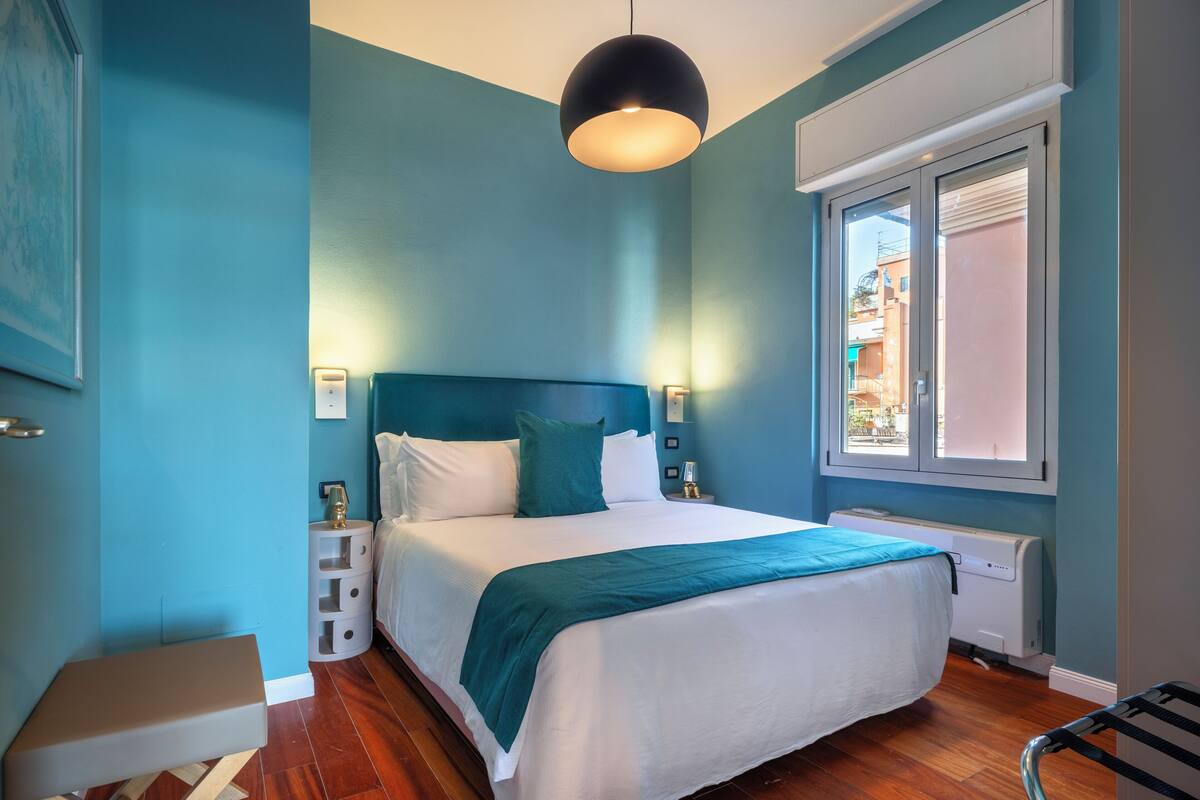 A bedroom with a bed, bedside tables, a window, and a hanging light fixture.