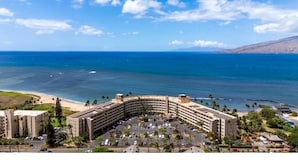 A hotel with a curved building, a parking lot, and a beach view. - Menehune Shores #423 2 Bedroom Condo by RedAwning (Kihei)