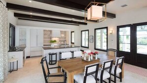 A modern kitchen with white cabinets, a central island, and a dining area with a wooden table and chairs.