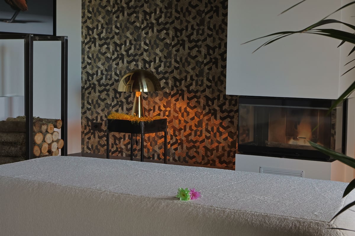 Une pièce avec un mur orné de motifs, une cheminée et une table sur laquelle est posé un objet décoratif.