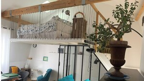 A cozy room with a loft bed, a dining table, and a comfortable seating area. - Loft Appart Proche Paris Chez Christine (Suresnes)