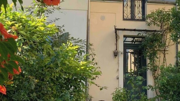A two-story building with a balcony and a door with a small garden area in front. - Loft Appart Proche Paris Chez Christine (Suresnes)