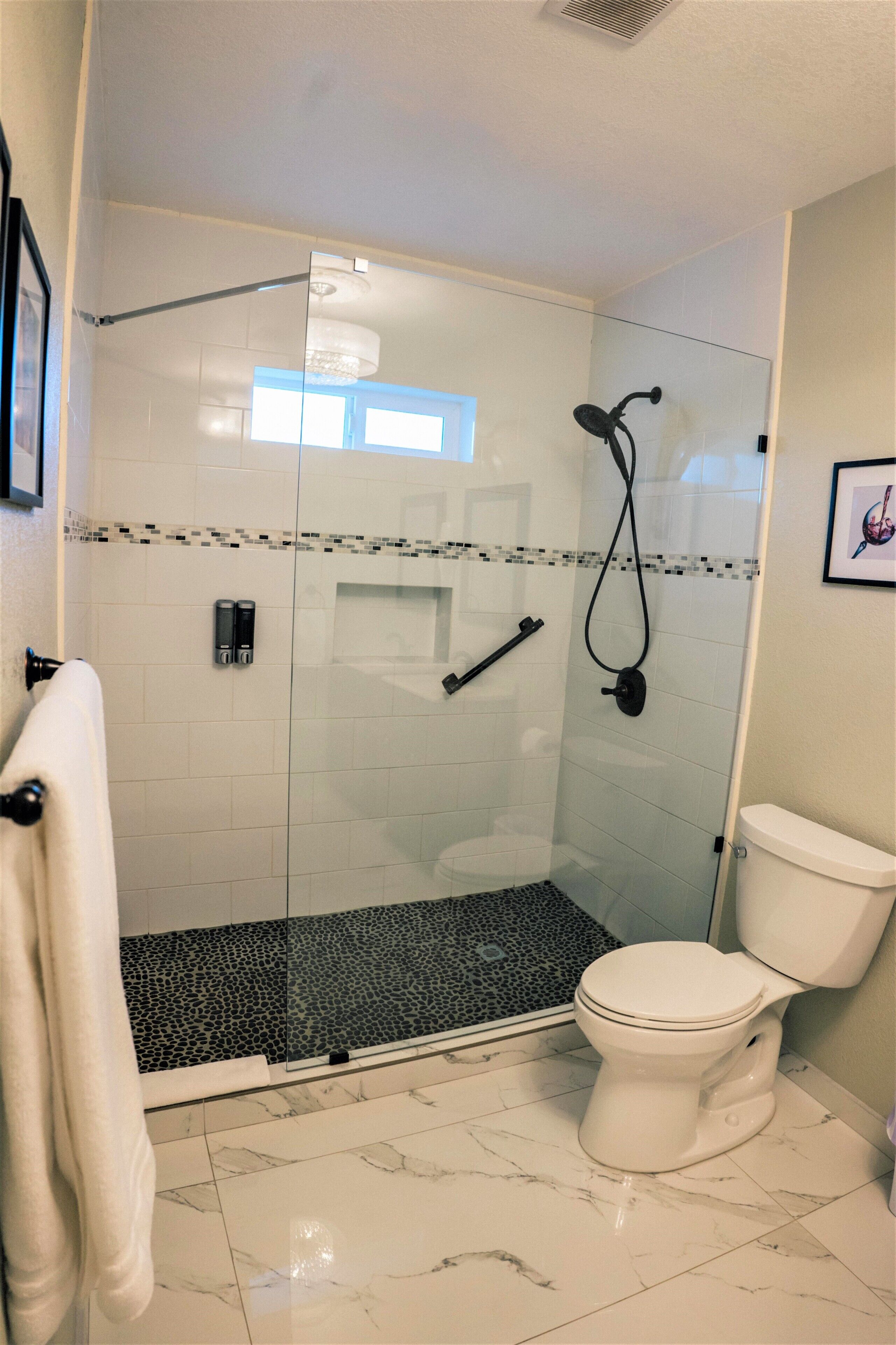 A modern bathroom with a glass-enclosed shower, a white toilet, and a marble floor.