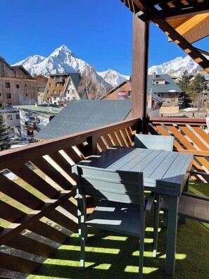 Eine Holzterrasse mit Tisch und Stühlen mit Blick auf ein Gebirge.