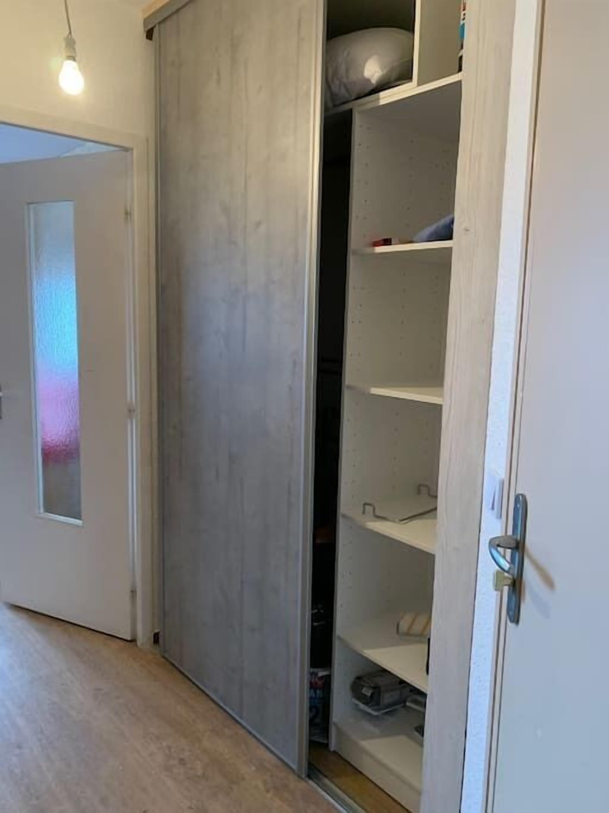 Ein Zimmer mit Schiebetürenschrank, einer Lampe und einer Tür mit Milchglas.