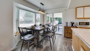 Eine moderne Küche mit einer großen Kochinsel, Holzschränken und einem Essbereich mit Tisch und Stühlen.