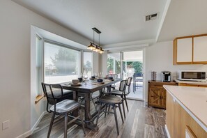 A modern kitchen with a wooden dining table, black chairs, and a built-in microwave. - Charming Rogue Valley Home in Central Point! (Central Point)